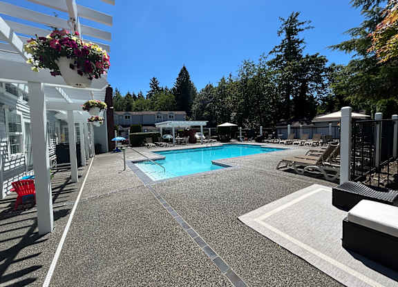 A pool area with a white fence and a red chair.