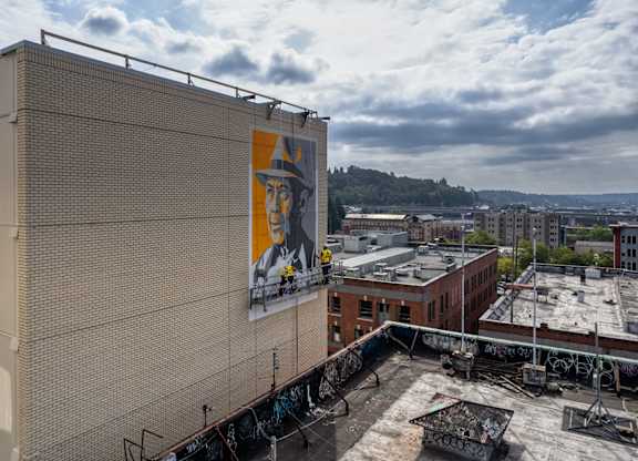 A large billboard with a man's face on it is on the side of a building.