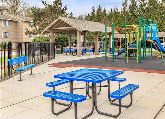 A playground with a blue picnic table and yellow slide.