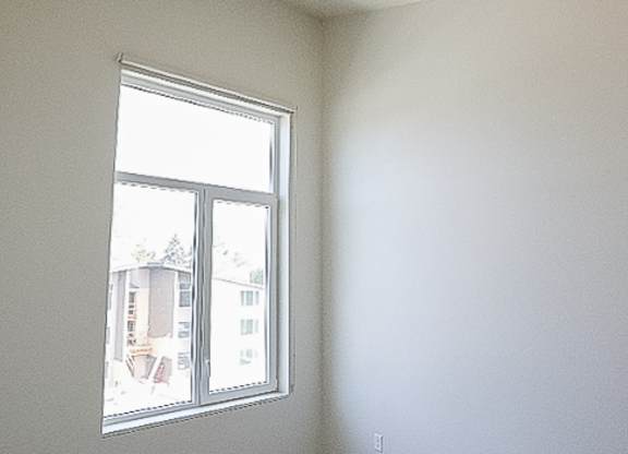 A room with a window and a view of a building outside.