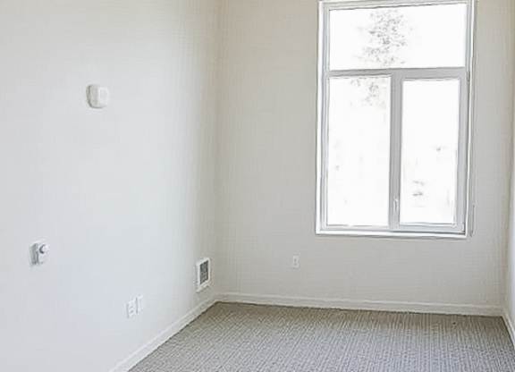 A room with a window and a carpeted floor.
