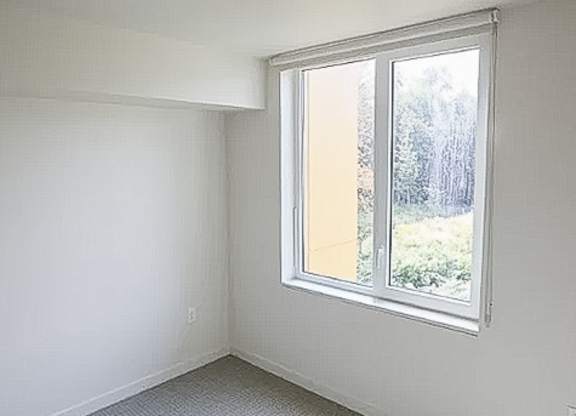 A room with a window and a grey carpet.