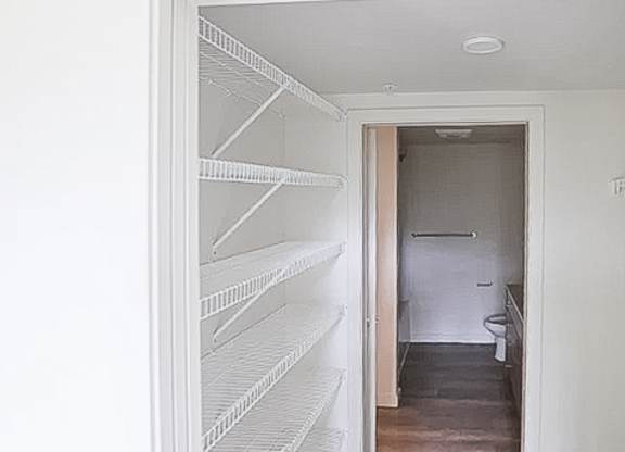A white pantry with a doorway leading to a bathroom.