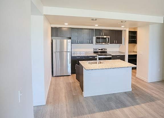 A modern kitchen with a stainless steel refrigerator and a granite countertop.