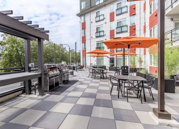 A patio with tables and chairs and umbrellas.