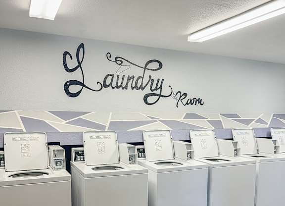 A laundry room with washing machines and a wall sign.