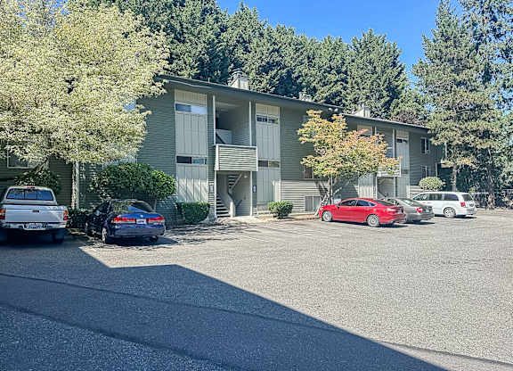 A parking lot in front of a building with cars parked.