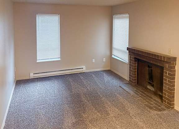 A room with a fireplace and two windows.