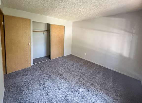 A room with a carpeted floor and two open doors.