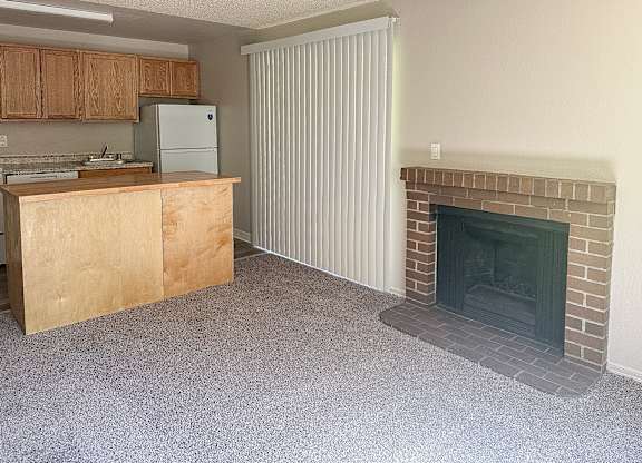 A kitchen with a refrigerator, sink, and a fireplace.