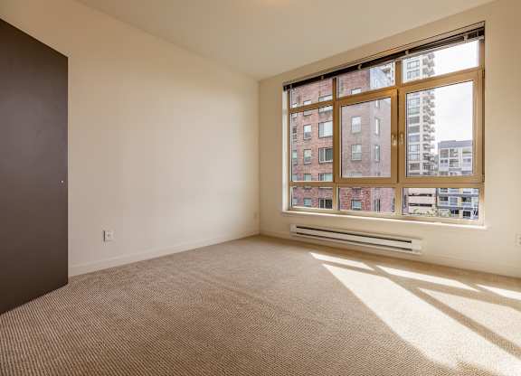 A room with a large window and a carpeted floor.