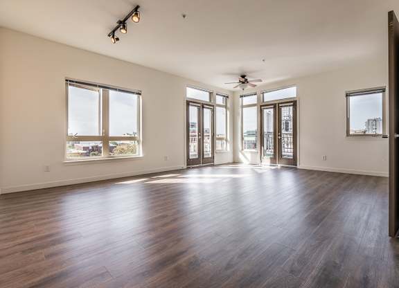 A spacious room with wooden floors and large windows.