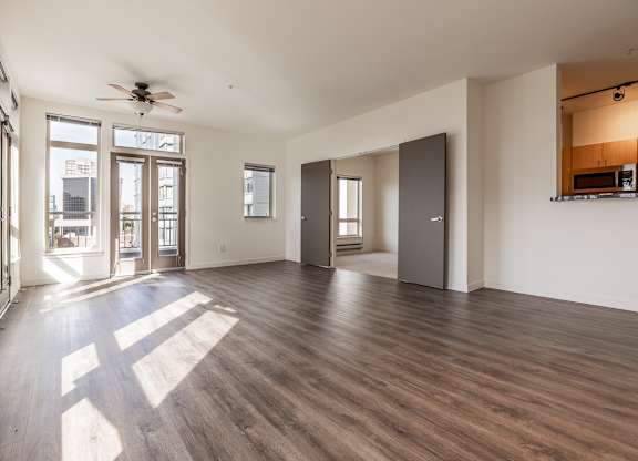 A spacious room with wooden floors and a ceiling fan.