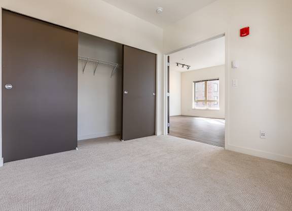A room with a carpeted floor and a door on the left.