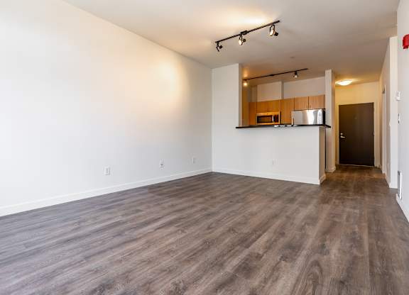 A spacious room with wooden flooring and a small kitchenette in the corner.