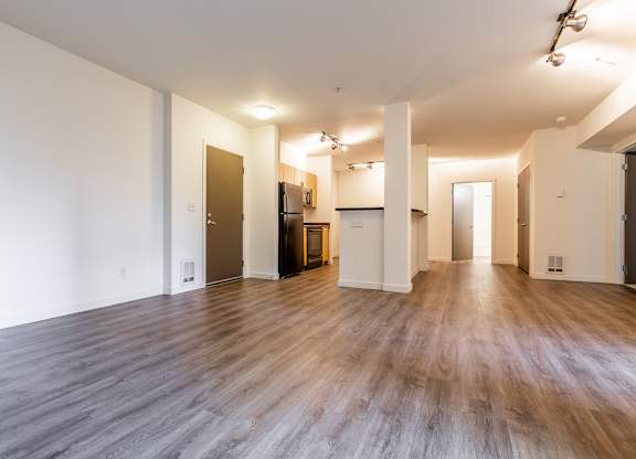A spacious room with wooden floors and white walls.