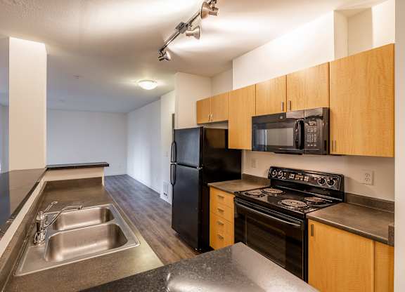 A kitchen with a black refrigerator, black stove, and black microwave.