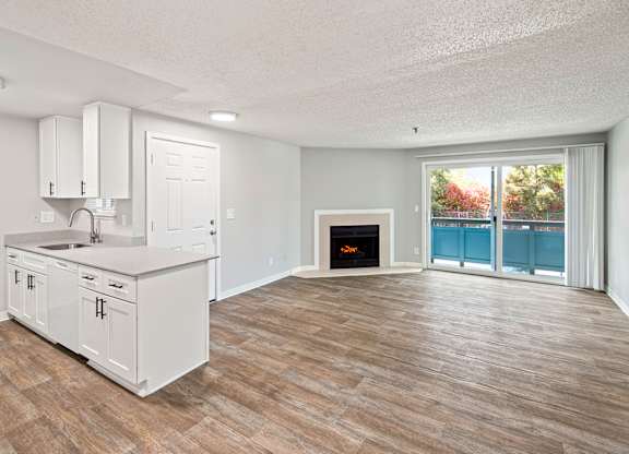 A kitchen with a fireplace and a view of a balcony.