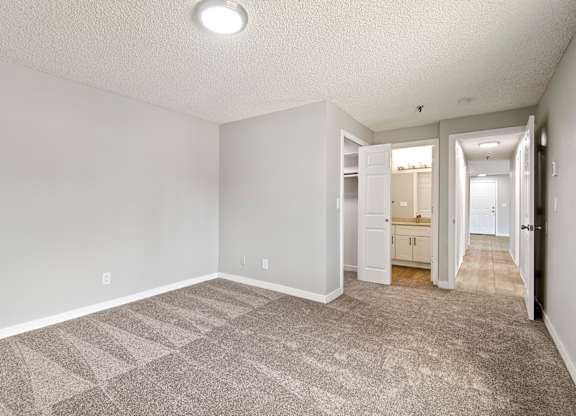 A spacious room with a carpeted floor and white walls.