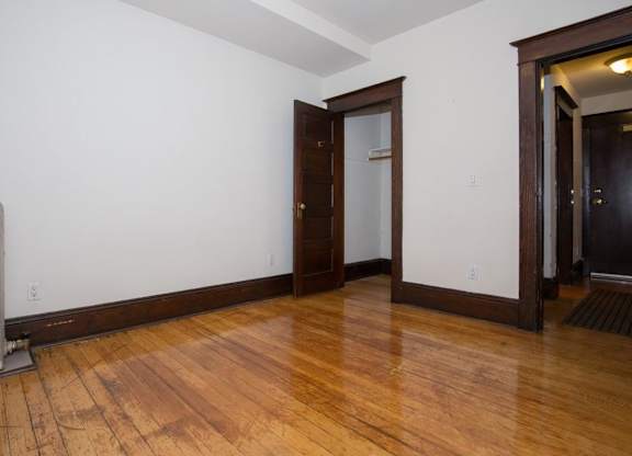 A room with wooden floors and a white wall with a door.