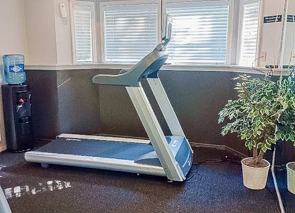 A treadmill is in a room with a plant and a water cooler.