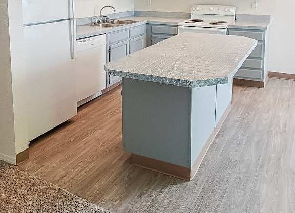 A kitchen with a white refrigerator and a countertop island.