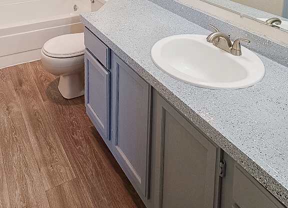 A bathroom with a toilet, sink, and mirror.