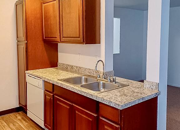 A kitchen with wooden cabinets and a white dishwasher.