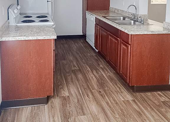 A kitchen with wooden cabinets and a white stove top oven.