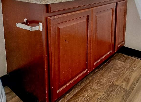 A bathroom with a brown cabinet and a marble counter.