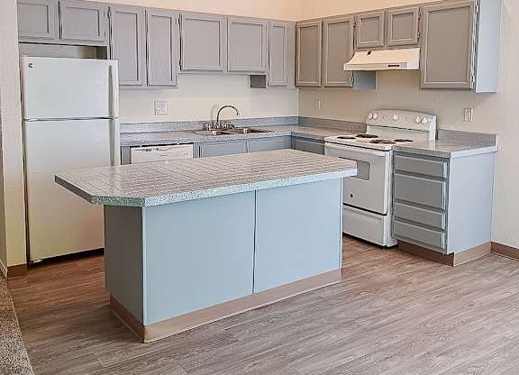 A kitchen with a white refrigerator and a marble island.