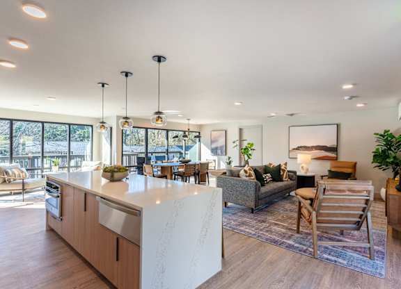 A modern kitchen with a large island and a living area with a couch and chairs.