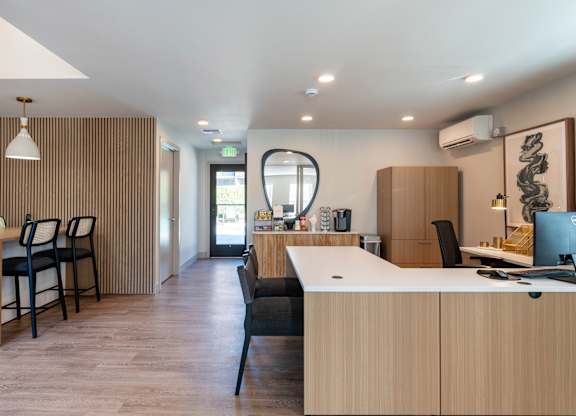 A modern office with wooden furniture and a large window.