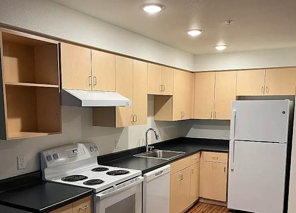 A kitchen with wooden floors and white appliances.