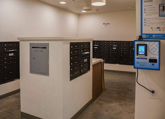 A rent drop box is in the middle of a wall of mailboxes.