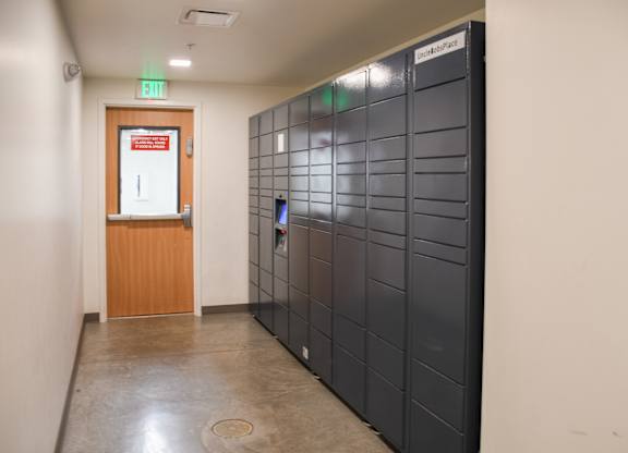 A hallway with a door and a wall of lockers.
