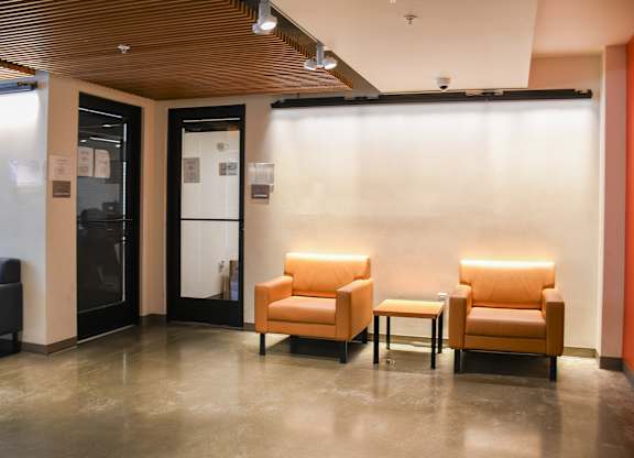 Two chairs and a table are in a room with a black door.