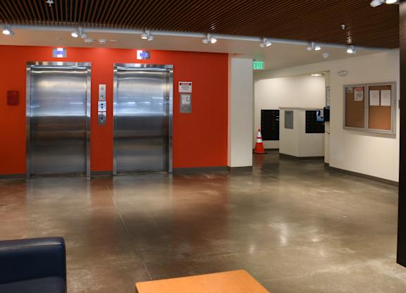 A hallway with two elevators and a door on the right.