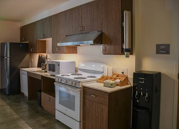 A kitchen with a white stove top oven and a black refrigerator.