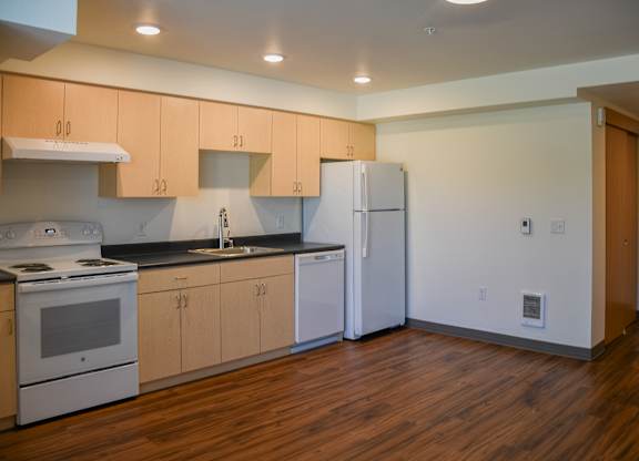 A kitchen with wooden floors and white appliances.