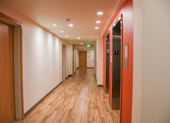 A long hallway with wood floors and a red wall on the right.