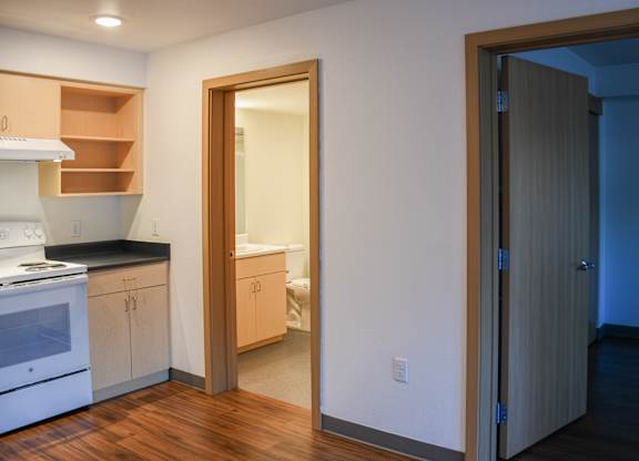 A kitchen with a white stove and wooden floors.