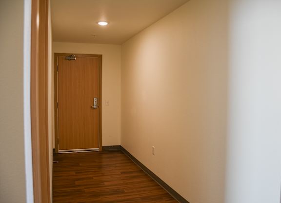 A hallway with a wooden door and a light on the ceiling.