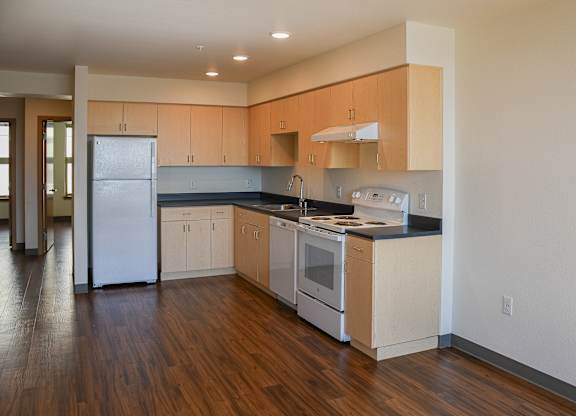 A kitchen with wooden floors and white appliances.