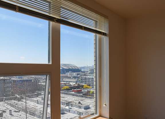 A view of a construction site through a window with blinds.