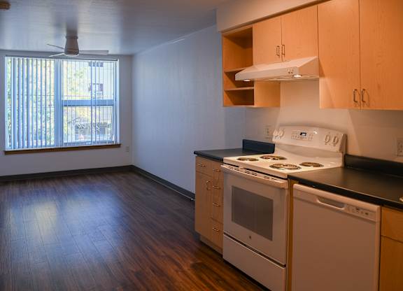 A kitchen with white appliances and wooden floors.
