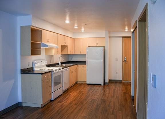 A kitchen with wooden floors and white appliances.