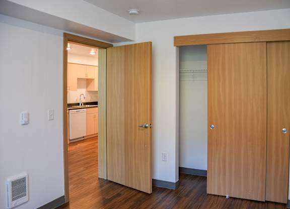 A kitchen with a white wall and a wooden door.