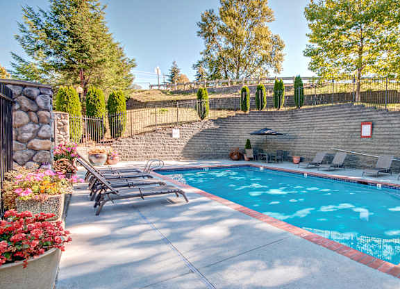 A pool surrounded by a stone wall and trees.