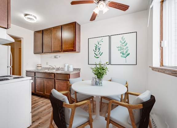 A kitchen with a white table and chairs and a plant on it.